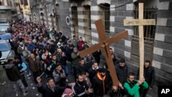 FILE - Syrian Christians carry crosses and shout slogans in Damascus, Syria, Dec. 24, 2024, as they march during a protest after a Christmas tree was set on fire in Hamah city.