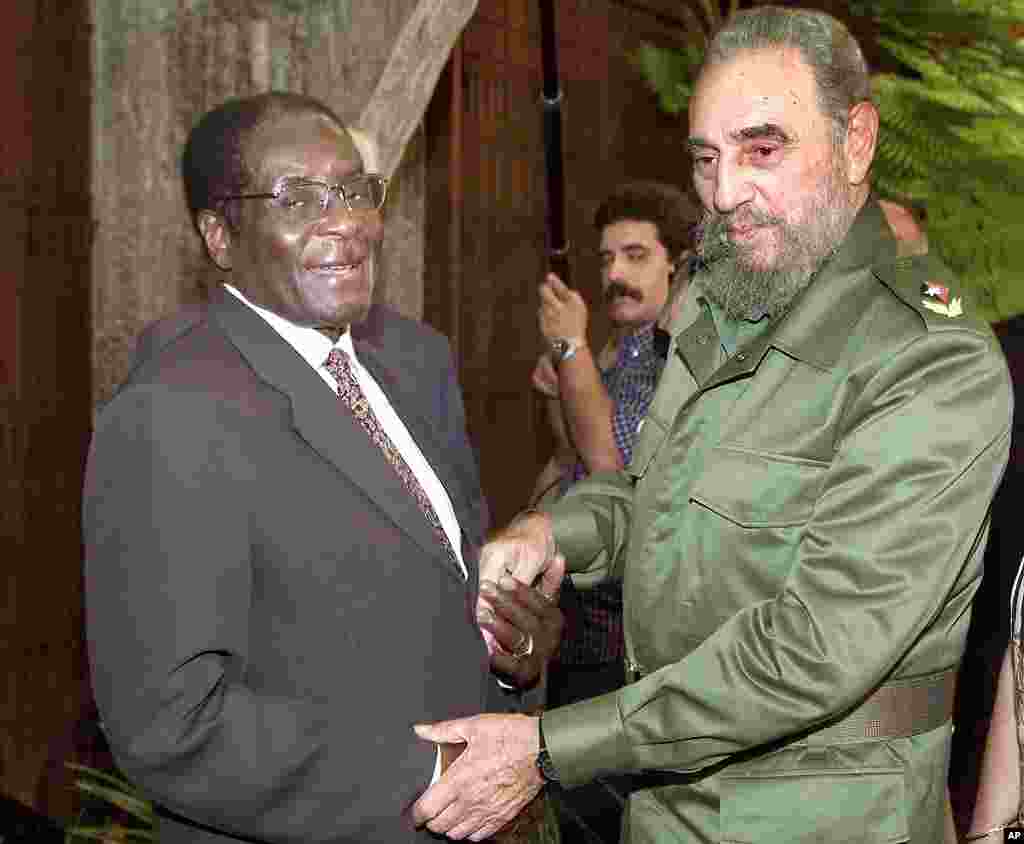 Zimbabwe's President Robert Mugabe, left, is welcomed by Cuban leader Fidel Castro at the Revolution Palace in Havana, Cuba, July 16, 2002. (AP)