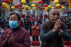 People wear masks as they pray at Wong Tai Sin temple on the first day of the Lunar New Year in Hong Kong, Jan. 25, 2020, as a preventative measure following a coronavirus outbreak that began in Wuhan, China.