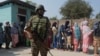 An Indian paramilitary soldier stands guard as Kashmiris queue up at a polling station to cast their vote during the second phase of assembly elections, on the outskirts of Srinagar, Indian-administered Kashmir, Sept. 25, 2024. (Wasim Nabi for VOA)