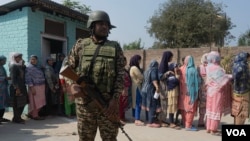 An Indian paramilitary soldier stands guard as Kashmiris queue up at a polling station to cast their vote during the second phase of assembly elections, on the outskirts of Srinagar, Indian-administered Kashmir, Sept. 25, 2024. (Wasim Nabi for VOA)