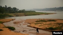 A man walks on a sandbar in the Paraguay River is pictured, amid smoke coming from wildfires in neighboring countries, as the river has hit a record low water level due to a major drought, in San Antonio, Paraguay, Sept. 7, 2024.