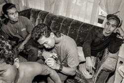 Cambodian Gino paints a gel tattoo on the arm of one of his friends in an apartment at a public housing building in Uptown, Chicago, 1990s. (Stuart Isett)