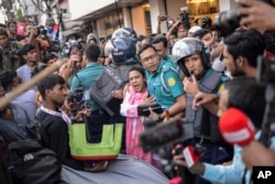 A police officer shields an Awami League woman supporter from students from anti-discrimination movements in Dhaka, Bangladesh, Nov. 10, 2024.