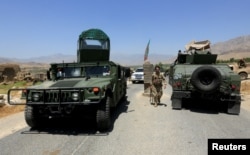 FILE - Afghan National Army soldiers patrol the area near a checkpoint recaptured from the Taliban, in the Alishing district of Laghman province, Afghanistan, July 8, 2021.