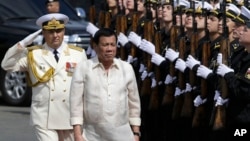 Philippine President Rodrigo Duterte, right, walks with Russian Rear Adm. Eduard Mikhailov, Deputy Commander of Flotilla of Pacific Fleet of Russia, during arrival honors as he visits the Russian anti-submarine Navy vessel Admiral Tributs in Manila.