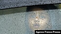 A child looks through the windshield of a car during a heavy rain shower in Chennai, India.