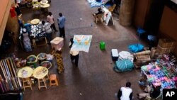 En plein centre d’un marché de Ouagadougou, Burkina Faso, un homme, au centre, arbore une carte avec le continent africain mardi 4 novembre 2014. Des émissaires internationaux ont tenté mardi de résoudre la crise politique au Burkina Faso, avec le spectre d’un vide de pouvoir imminent après la chute du président Blaise Compaoré qui a fait 27 ans au pouvoir. (AP Photo / Theo Renaut)