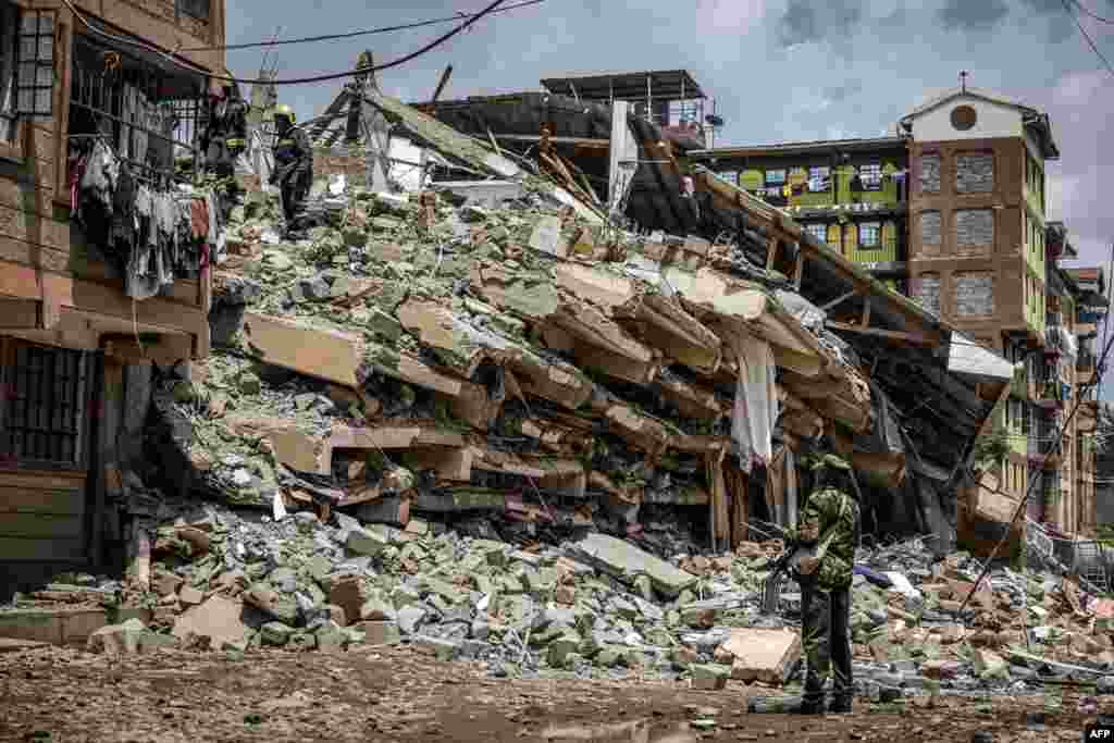 Kenya Police officer and Nairobi County emergency responders inspect the rubble of a collapsed residential building at Kahawa West residential area in Nairobi.