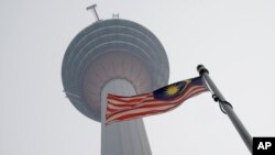 Bendera nasional Malaysia berkibar di bawah Menara KL yang diselimuti kabut di Kuala Lumpur, Malaysia, Rabu, 18 September 2019. (Foto: AP)