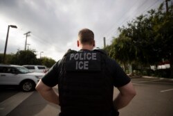 FILE - A U.S. Immigration and Customs Enforcement officer looks on during an operation in Escondido, Calif., July 8, 2019.