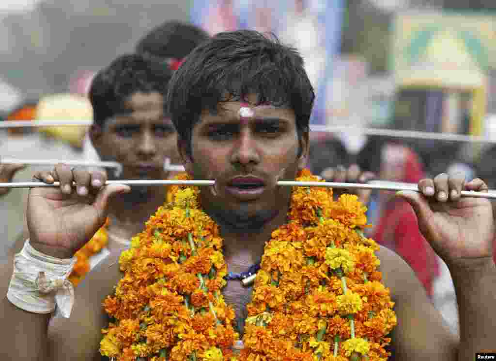 Devotees with their mouth pierced with rods participate in an annual religious procession as part of a ritual to worship the Hindu goddess Maha Mariamman in the northern Indian city of Amritsar.