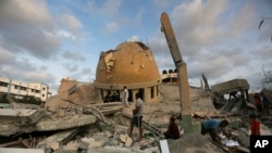 FILE - People stand outside a mosque destroyed in an Israeli air strike in Khan Younis, Gaza Strip, October.8, 2023.