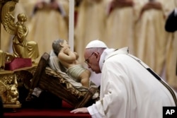 Pope Francis kisses a statue of Baby Jesus as he celebrates the Christmas Eve Mass in St. Peter's Basilica at the Vatican, Dec. 24, 2015.