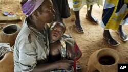 Abdou Sawadogo, 3, is held by his mother as he waits to be given medicine by Red Cross workers at the Nicla II refugee camp, which houses people who have been driven from their land, in Guiglo in western Ivory Coast (File Photo)