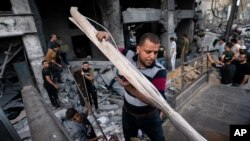People salvage items from inside the severely damaged Al-Jawhara building following a cease-fire reached after an 11-day war between Gaza's Hamas rulers and Israel, in Gaza City, May 21, 2021.