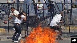 People take cover as police clash with dozens of stone-throwing Kurdish protesters at a peace rally that turned violent in Istanbul, Turkey, September 1, 2011.