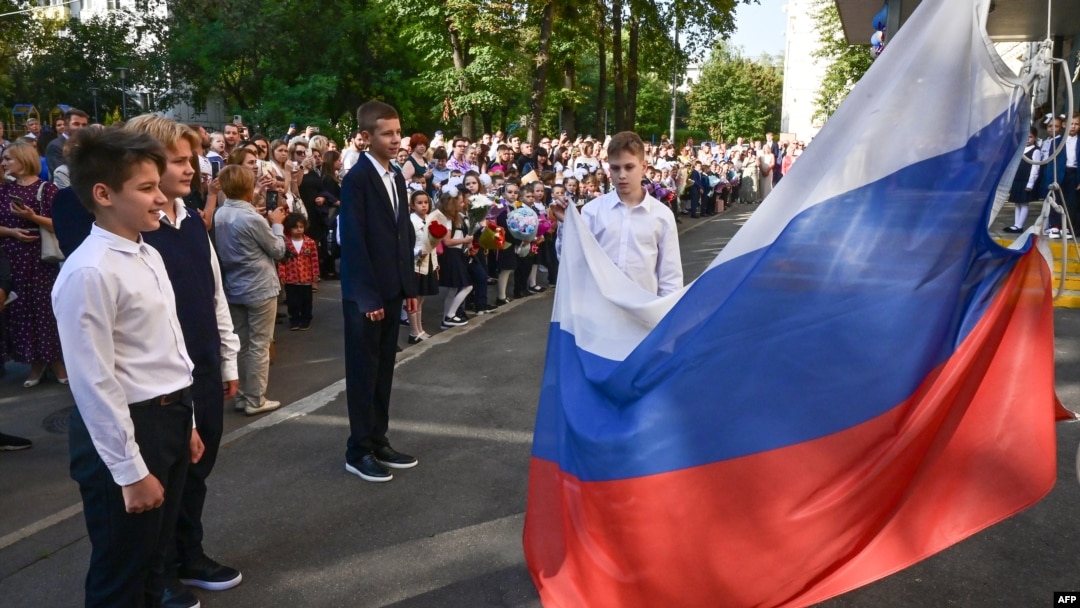 Российские школьники поднимают российский национальный флаг во время церемонии «первого звонка», посвященной началу учебного года в Москве 1 сентября 2023 года.