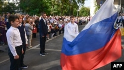 Российские школьники поднимают российский национальный флаг во время церемонии «первого звонка», посвященной началу учебного года в Москве 1 сентября 2023 года.