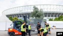 Para pekerja membereskan penghalang di depan Ernst Happel Stadium yang tadinya akan dipakai untuk konser Taylor Swift, di Wina, Austria, Kamis, 8 Agustus 2024. (Foto: Florian Wieser/AP)