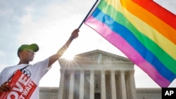 Carlos McKnight, warga Washington, mengibarkan bendera pelangi sebagai tanda hak-hak kaum gay di depan gedung Mahkamah Agung AS di Washington, D.C. (26/6). 