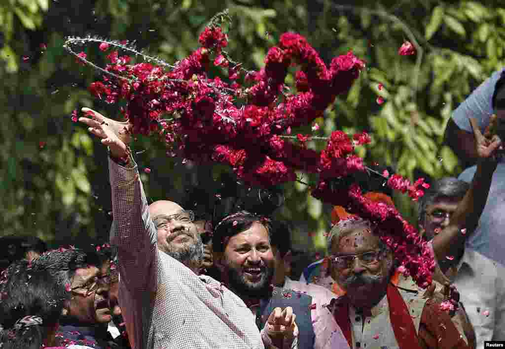 Amit Shah, um líder sénior do Partido do Povo ou&nbsp;Bharatiya Janata Party (BJP), atira coroas de flores aos apoiantes do BJP, durante os festejos depois de serem conhecidos os resultados das eleições, na sede do partido, Nova Deli, Maio 16, 2014.