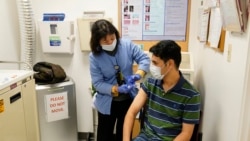 A newly arrived refugee from Afghanistan receives a vaccination from medical assistant Catherine Pham at the Valley Health Center TB/Refugee Program in San Jose, California on December 9, 2021. (AP Photo/Eric Risberg)