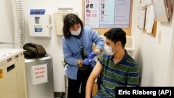 A newly arrived refugee from Afghanistan receives a vaccination from medical assistant Catherine Pham at the Valley Health Center TB/Refugee Program in San Jose, California on December 9, 2021. (AP Photo/Eric Risberg)