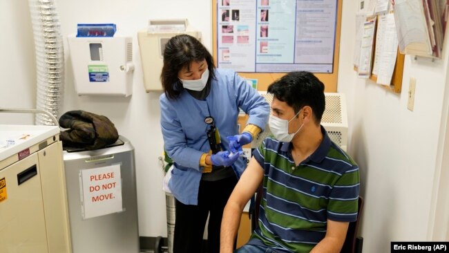 A newly arrived refugee from Afghanistan receives a vaccination from medical assistant Catherine Pham at the Valley Health Center TB/Refugee Program in San Jose, California on December 9, 2021. (AP Photo/Eric Risberg)