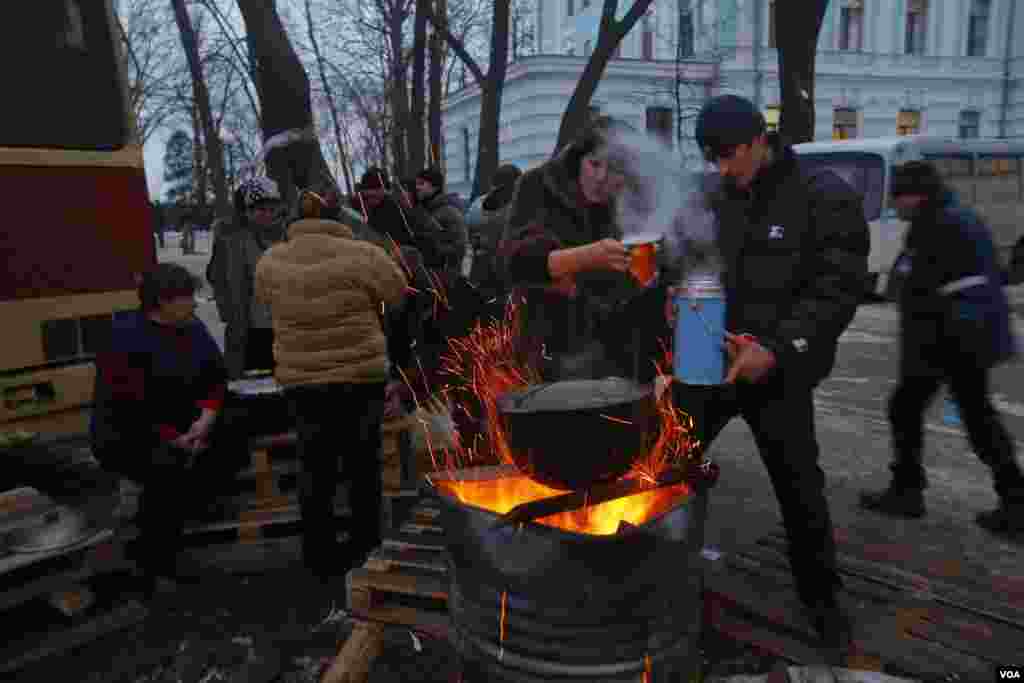 Para pendukung Presiden Viktor Yanukovych dari Partai Daerah meminum teh dekat api selama protes di Kiev, 15 Desember 2013.