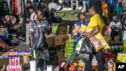 People shop at an informal and illegal market that pops up at night to avoid police raids in central Harare, Zimbabwe, Friday, Nov. 11, 2024. (AP Photo/Aaron Ufumeli)