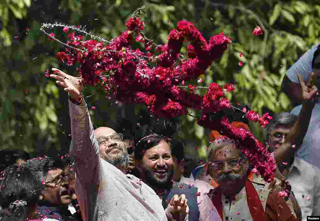 Amit Shah, a senior leader of the Bharatiya Janata Party (BJP), throws garlands towards BJP supporters during celebrations after learning of poll results outside the party headquarters, in New Delhi, May 16, 2014.