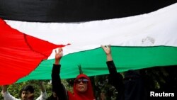 Demonstran memegang bendera Palestina dalam demonstrasi di depan Kedutaan Besar Amerika di Jakarta, untuk mengecam keputusan AS mengakui Yerusalem sebagai Ibu Kota Israel, 8 Desember 2017.