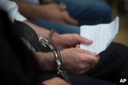 FILE - Syrian immigrant Ahmed Hamed holds a paper in his hands in the courtroom during his appeal trial in the appeals court in Szeged, 170 kms southeast of Budapest, Hungary, June 15, 2017.