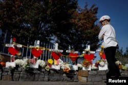 FILE - Marybeth Kelly looks at memorials along a bike path to remember the victims of the New York Oct. 31 attack, in New York City, Nov. 3, 2017.