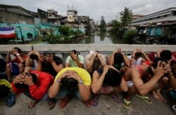 FILE - Filipino men place their hands over their heads as they are rounded up during a police operation as part of the continuing "War on Drugs" campaign of Philippine President Rodrigo Duterte in Manila, Philippines, Oct. 7, 2016.