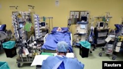 A member of the medical staff in a protective suit is seen in front of a patient diagnosed with coronavirus disease in an intensive care unit at the San Raffaele hospital in Milan, Italy.