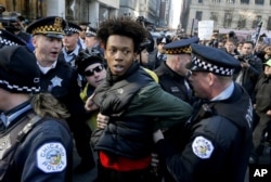 Lamon Reccord is taken into custody by Chicago police officers during a march calling for Chicago Mayor Rahm Emanuel and Cook County State's Attorney Anita Alvarez to resign, Dec. 9, 2015.