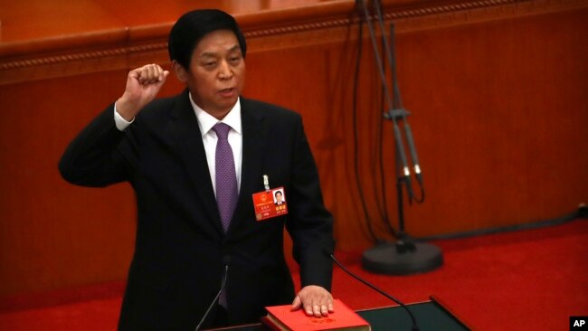 新当选的中国人大委员长栗战书2018年3月17日在全国人大全体会议上手按宪法，宣誓就职。