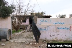 The word “Daeshy,” meaning IS militant, is scrawled on a burnt-out house once belonging to a militant in a village outside of Mosul city in Iraq, Nov. 27, 2018.