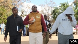 FILE - Holding a Bible, Pastor Evan Mawarire walks into the court building while handcuffed to his driver, Ocean Chihota, in Harare, Zimbabwe, June 28, 2017. (S. Mhofu/VOA)