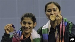 India's Jwala Gutta, right, and Ashwini Ponnappa Machimanda show the gold medals they won in the women's badminton doubles event during the Commonwealth Games at Siri Fort Sports Complex in New Delhi, India, 14Oct. 2010.