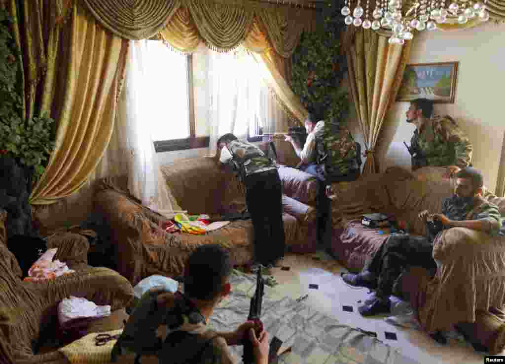 A Free Syrian Army fighter fires his sniper rifle from a house in Aleppo August 14, 2012.