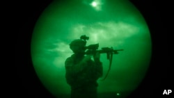 FILE - A US soldier patrols at night in Khost province, Afghanistan, seen through night vision equipment in this 2008 file photo.