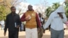 FILE - Holding a Bible, Pastor Evan Mawarire walks into the court building while handcuffed to his driver, Ocean Chihota, in Harare, Zimbabwe, June 28, 2017. (S. Mhofu/VOA)