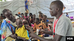 Gatwuech Madit, a nutrition promoter with Save the Children in Akobo, measures the mid-upper arm circumference of a child at Koat Nutrition Center to assess malnutrition, June 17, 2024. (Sheila Ponnie/VOA)