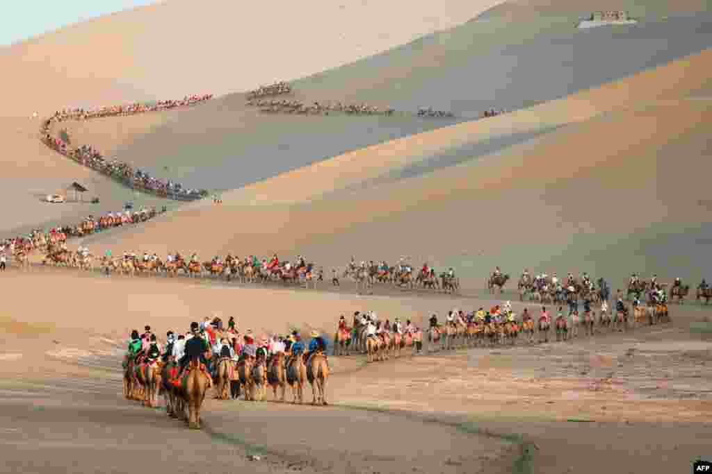 Tourists ride camels in the desert in Dunhuang in China&#39;s northwestern Gansu province.