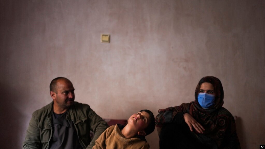 Sanam, a bacha posh, a girl living as a boy, sits next to her mother and father during an interview in their house, in Kabul, Afghanistan, Dec. 7, 2021.