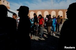 FILE - Migrants wait in line for food at a camp containing hundreds of migrants who arrived at the U.S. border from Central America in a caravan with the intention of applying for asylum in the U.S., in Tijuana, Mexico, Dec. 12, 2018.