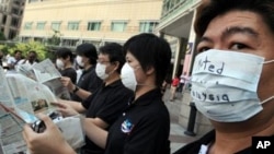 Activists wearing masks pretent to read newspapers upside down during a silent protest to support freedom of the press, outside a shopping mall in Kuala Lumpur (File Photo)